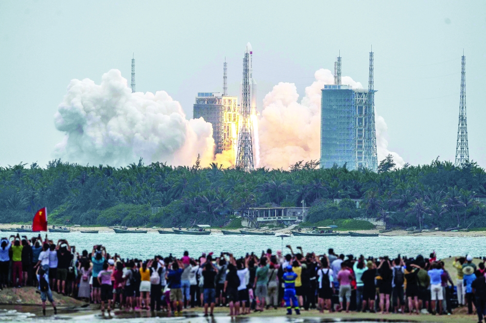 People watch a Long March 5B rocket, carrying China's Tianhe space station core module, as it lifts off from the Wenchang Space Launch Centre in Hainan province. - AFP 