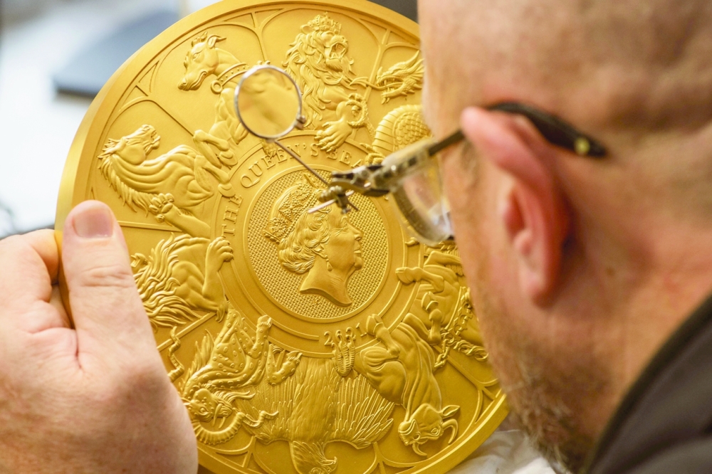 A man inspects a 10-kilogram commemorative gold coin marking the conclusion of the Queen's Beasts collection, at The Royal Mint, South Wales. - Reuters