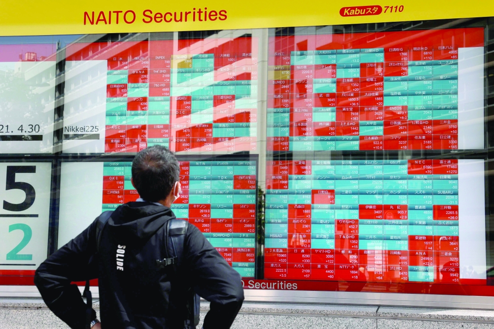A pedestrian looks at Japanese companies' share prices of the Tokyo Stock Exchange displayed on an electronic board in Tokyo. - AFP 