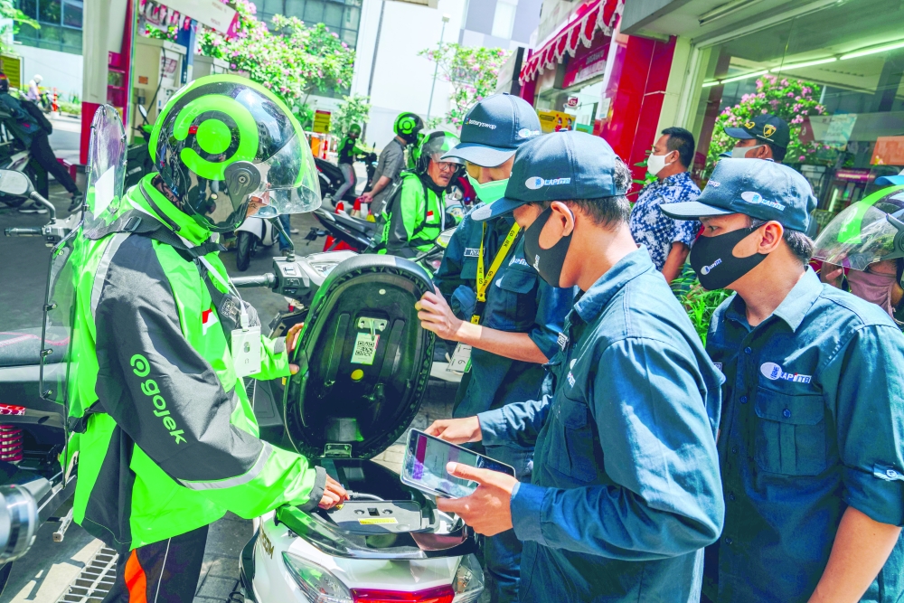 A Gojek taxi rider charges his motorbike's battery at a charging station in Jakarta. - Reuters
