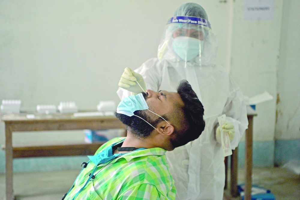 A health worker wearing protective gear collects a nasal swab sample of an election counting agent to test for the coronavirus at Siliguri college counting centre in Siliguri. - AFP 