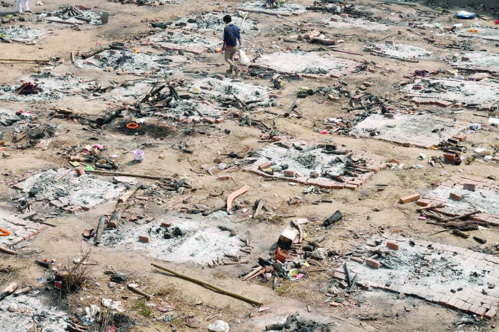 A relative collects the remains of coronavirus victim after a mass cremation at a cremation ground in New Delhi. - AFP 