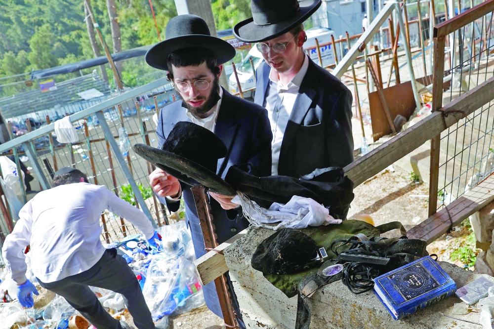 A man checks the personal belongings of pilgrims, piled up at the scene of a stampede that took place during a religious gathering overnight in the northern Israeli town of Meron naer the reputed tomb of Rabbi Shimon Bar Yochai. - AFP 