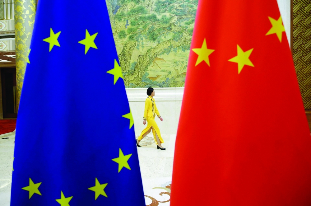An attendant walks past EU and China flags at Diaoyutai State Guesthouse in Beijing, in this file photo. — Reuters