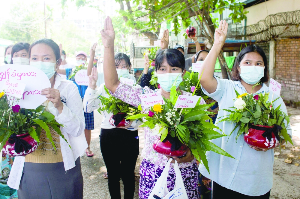 Women carry pots with flowers as they take part in a protest against the military coup in Yangon, recently. - Reuters file photo