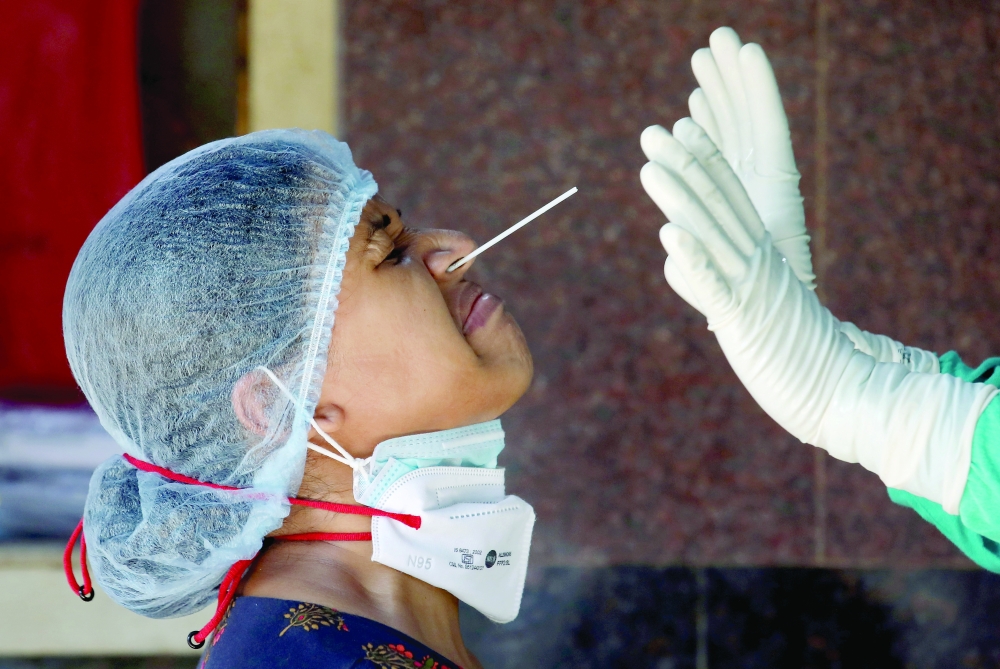A woman reacts as a healthcare worker takes a nasal swab sample for a coronavirus disease test at a government-run hospital in Kolkata. - Reuters