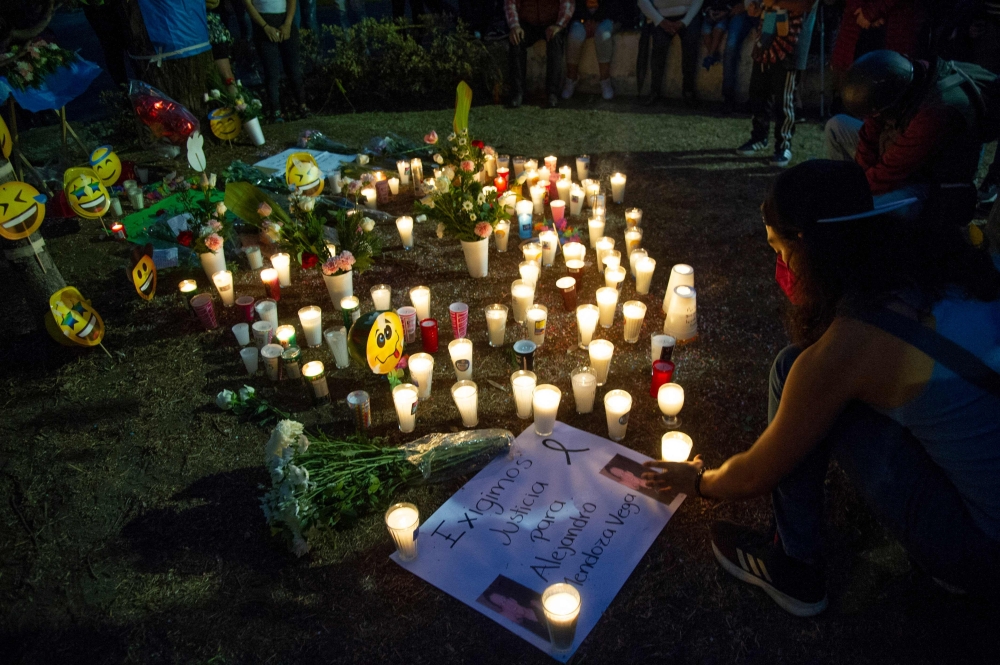 A person places a candle down near the site of a train accident where an elevated metro line partially collapsed, during an event in honor of the victims in Mexico City. - AFP
