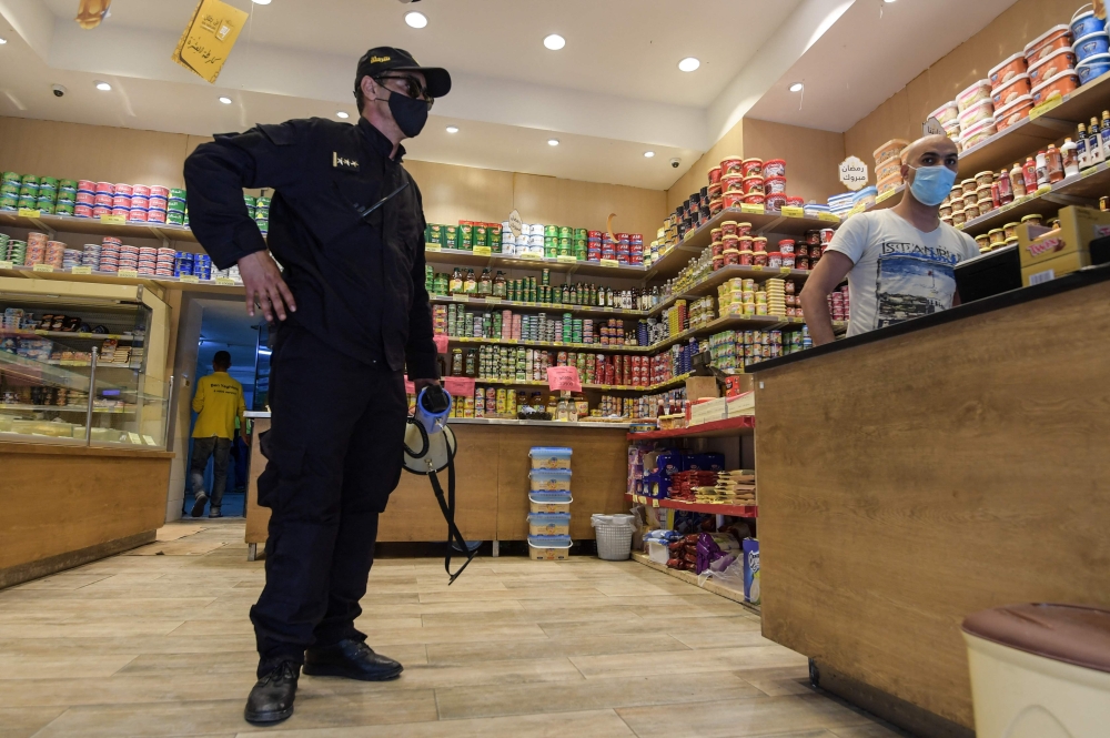 A Tunisian police officer controls a food shop, amid a general confinement imposed by the authorities in a bid to slow down a surge in coronavirus infections, in Tunis. - AFP