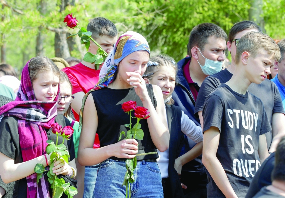 Mourners stand near the grave of Elvira Ignatieva, an English language teacher killed in the massacre at School Number 175, during a funeral at a cemetery in Kazan, on Wednesday. - Reuters