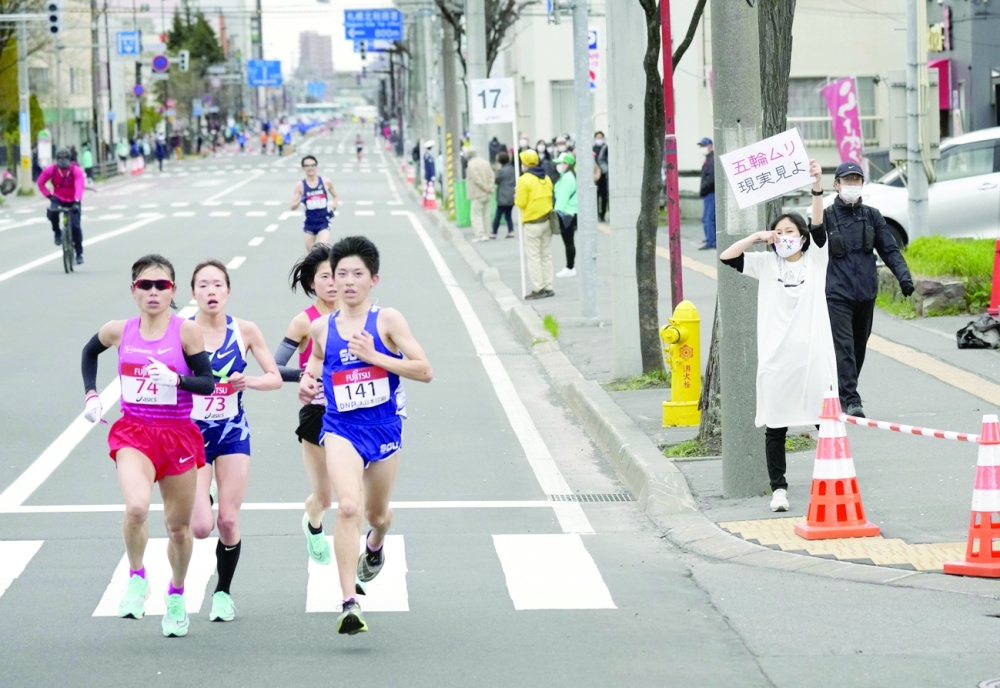A spectator raises a paper sign reading 'It is impossible to hold the Olympics, face up to reality' along the race route during a test event for the Tokyo 2020 Olympics. -- Reuters