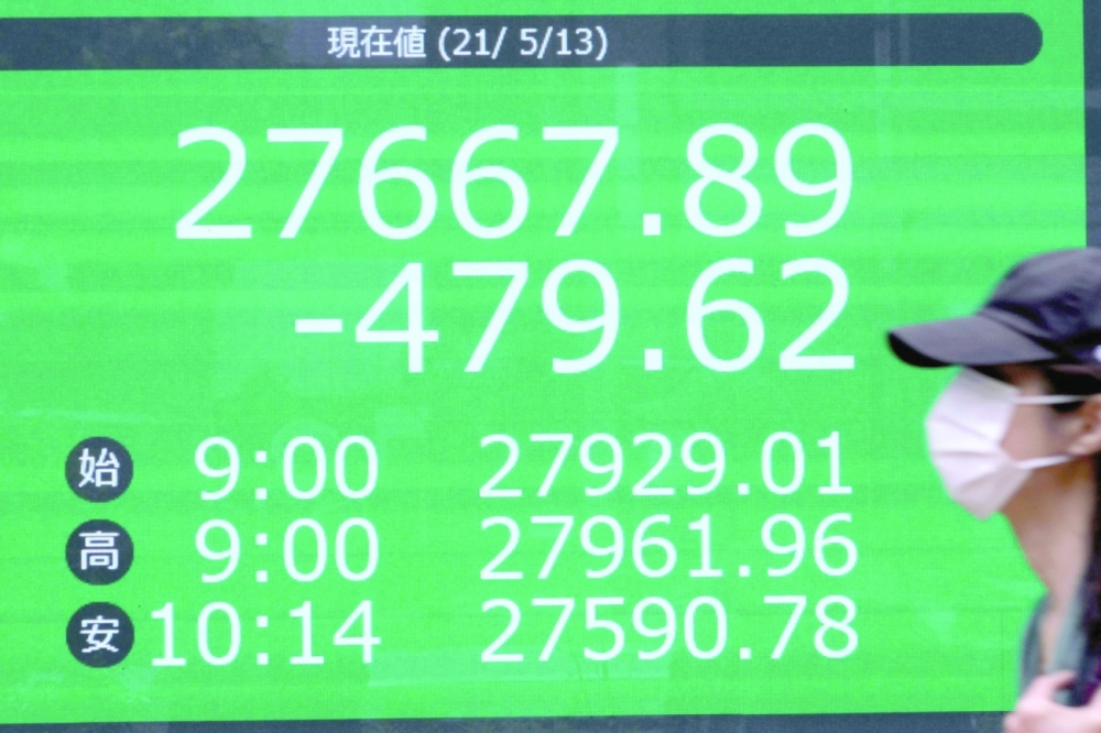 A man walks past an electronic quotation board displaying share prices in early morning trading on the Tokyo Stock Exchange in Tokyo. - AFP