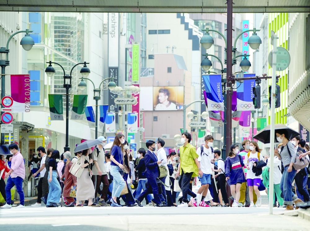 Passersby wearing protective face masks walk under the street decoration of Tokyo 2020 Olympic and Paralympic Games due to the coronavirus outbreak in Tokyo. - Reuters 