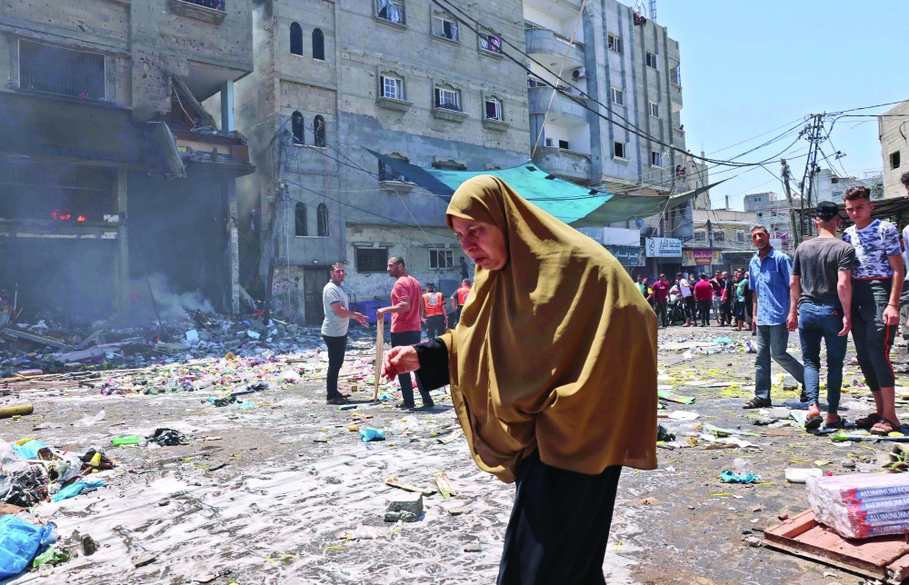A Palestinian woman walks amidst the rubble following an Israeli strike on Rafah in the southern Gaza Strip. - AFP 