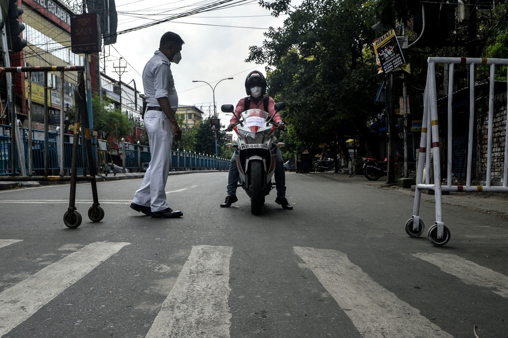 A police personnel stops a commuter at a check point during a 15-day partial lockdown imposed to curb the spread of the Covid-19 coronavirus, in Siliguri on May 16, 2021. / AFP / Diptendu DUTTA