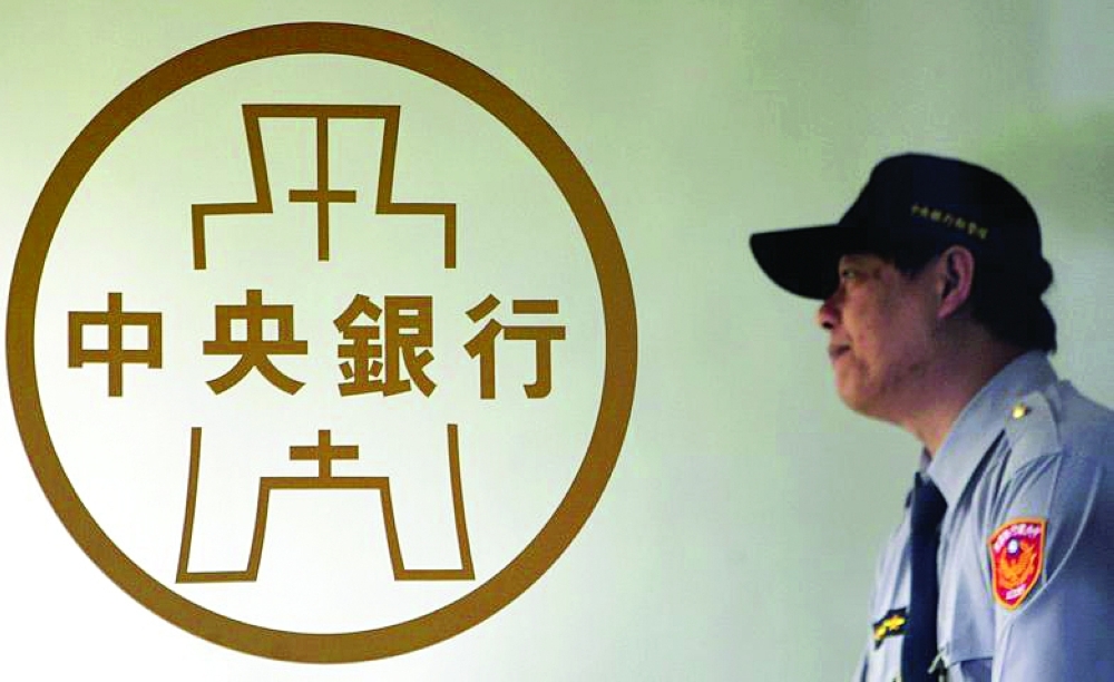 A police officer stands beside the Taiwan Central Bank logo in Taipei. — Reuters