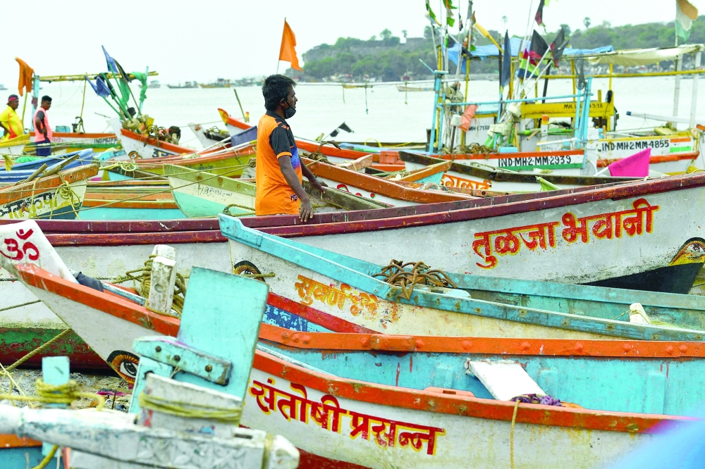 Fishermen are seen next to boats being moored at a fishing village off the city coast in the wake of the impending cyclone Tauktae in Mumbai. - AFP

