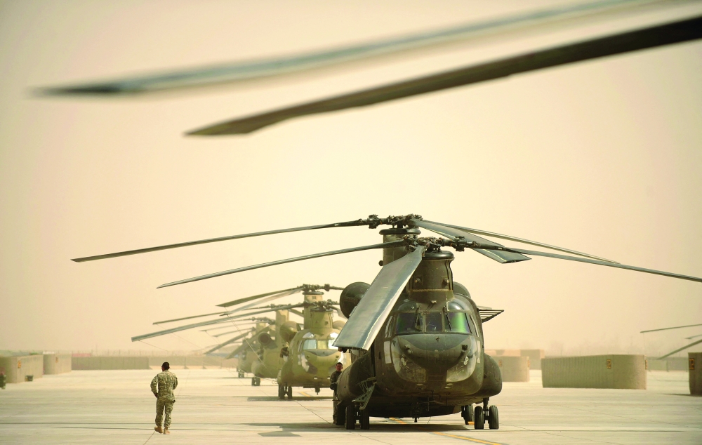 A US airman walks past a row of Chinook helicopters at Kandahar airbase in southern Afghanistan. - AFP File Photo