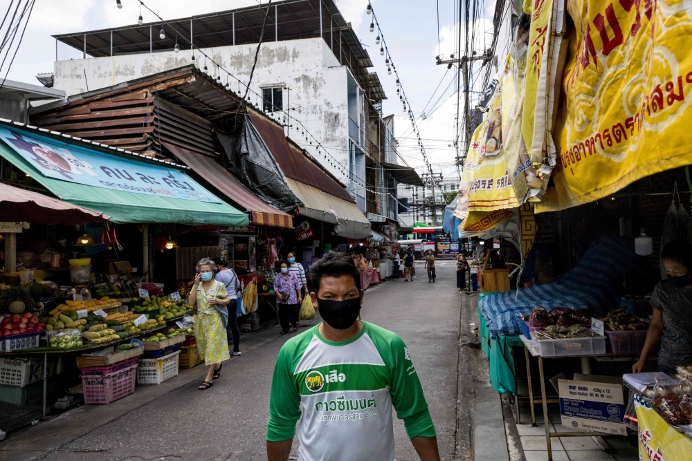 A man wearing a face mask walks past food stalls in Bangkok on May 17, 2021, as Thailand's economy shrank in the first quarter, official data showed Monday, battered by coronavirus restrictions. / AFP / Jack TAYLOR

