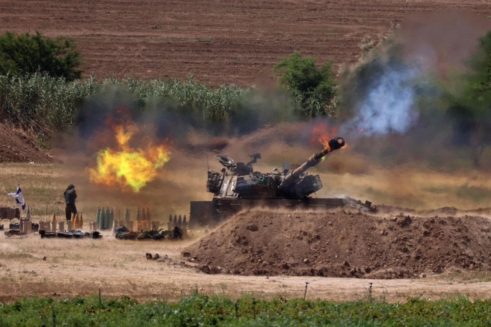 Israeli soldiers fire a 155mm self-propelled howitzer towards the Gaza Strip from their position along the border with the Palestinian enclave, on May 17, 2021. / AFP / EMMANUEL DUNAND

