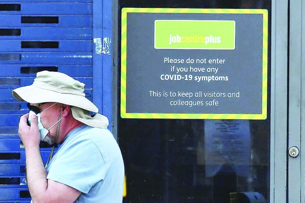 A person wearing a protective face mask walks past a Job Centre Plus office in London. — Reuters