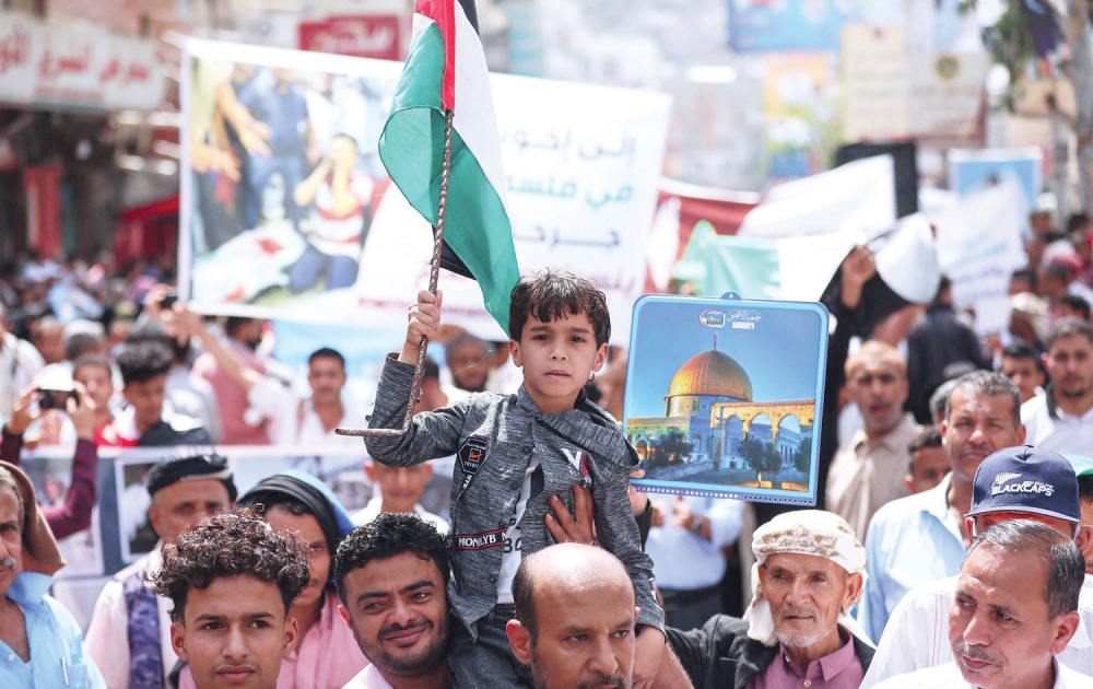 A Yemeni boy holds a Palestinian national flag during a demonstration held in Yemen’s third city Taez to denounce the continuing Israeli air strikes on the Gaza Strip on Wednesday. — AFP