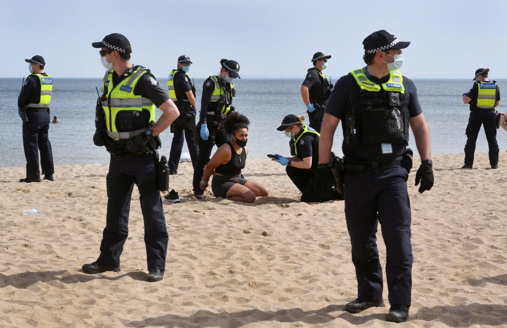 This file photo shows police surrounding an anti-lockdown protester as they detain her in Elwood Beach in Melbourne. Prime Minister Scott Morrison defended his "Fortress Australia" Covid-19 restrictions on May 18, 2021
