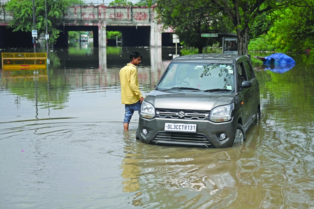 A car half submerged in a waterlogged street after it rained in New Delhi. - AFP