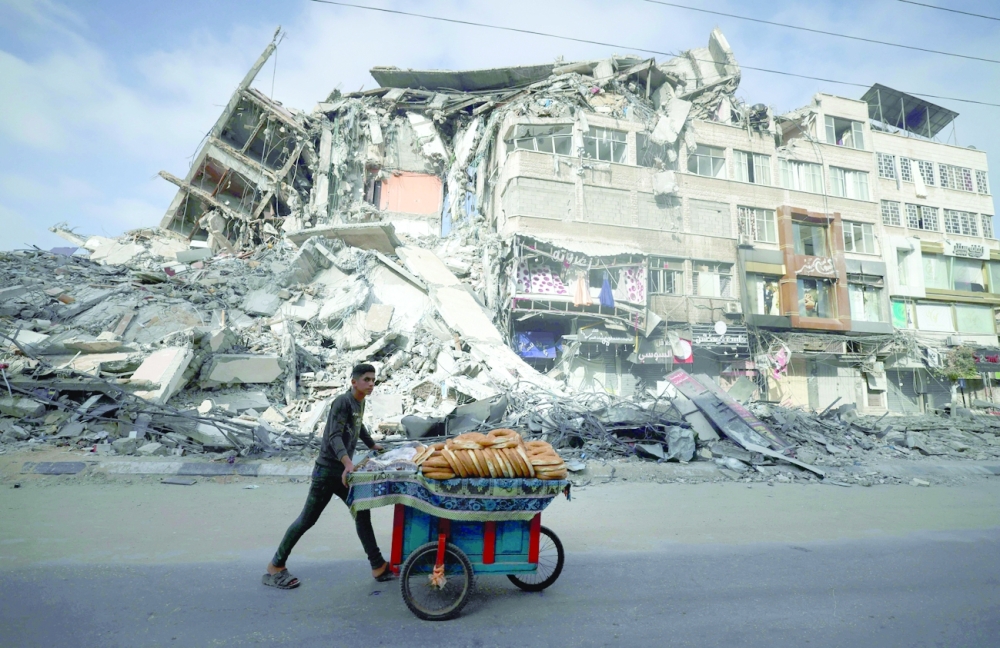 A Palestinian man walks past the destroyed Al Shuruq building in Gaza City. - AFP 