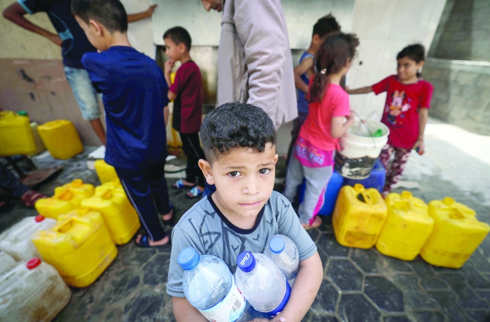 Palestinian children fill up containers with water in Gaza City. - AFP