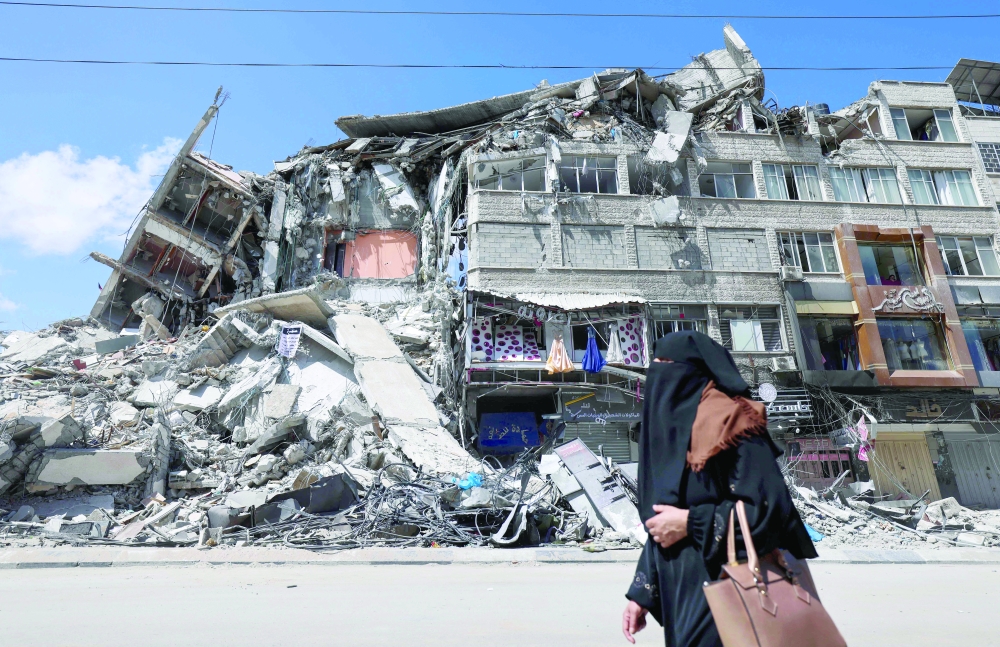 A Palestinian woman walks past a destroyed building in the Al Rimal commercial district in Gaza City. - AFP