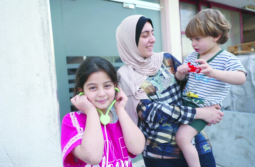 Maysa Abu al Awf plays with her 2-year-old brother Ahmad and 7-year-old sister Maram, at their grandfather's home in Gaza City. - AFP