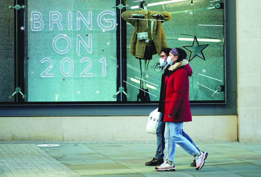 People walk past a sign in a shop window amid the outbreak of Covid-19 in Manchester, Britain. — Reuters