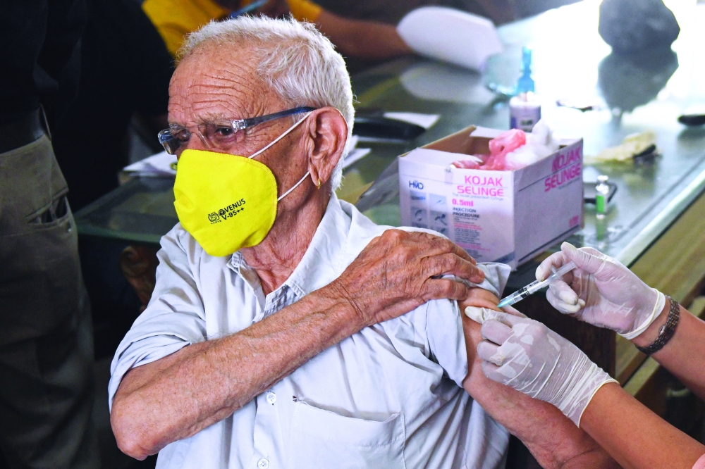 A health worker inoculates a man with a dose of the coronavirus vaccine at a vaccination camp held at a wholesale vegetable market on the outskirts of Amritsar. - AFP 