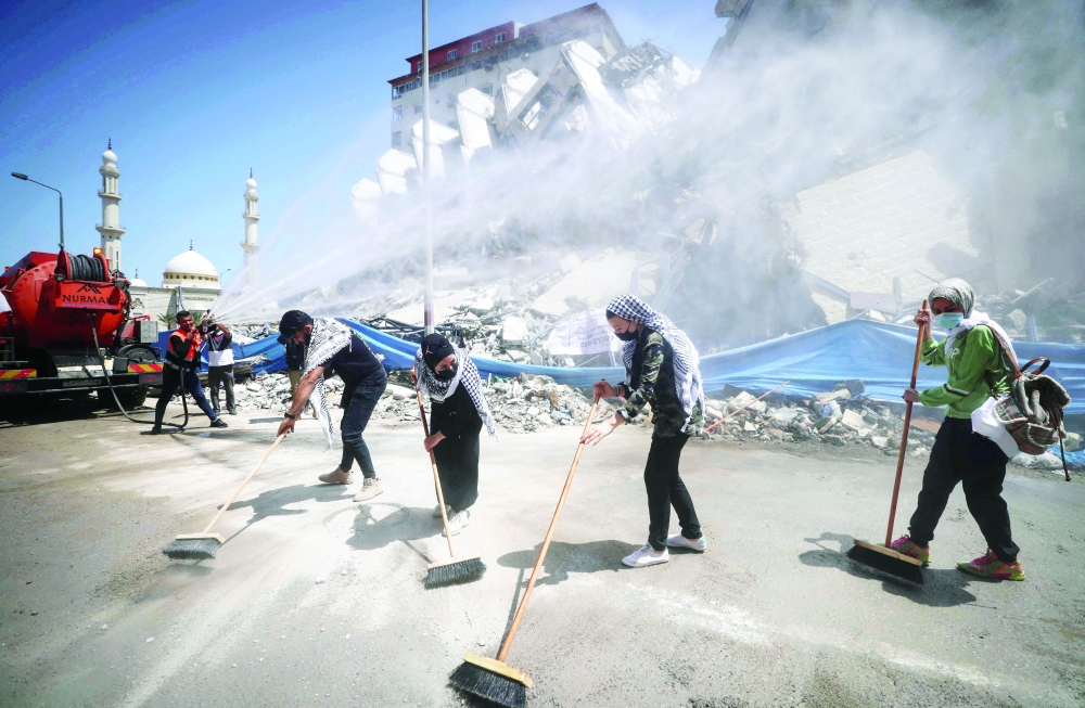 Palestinian volunteers and municipal workers clear the rubble of the Hanadi compound, recently destroyed by Israeli strikes, in Gaza City’s Rimal district, on Tuesday. — AFP