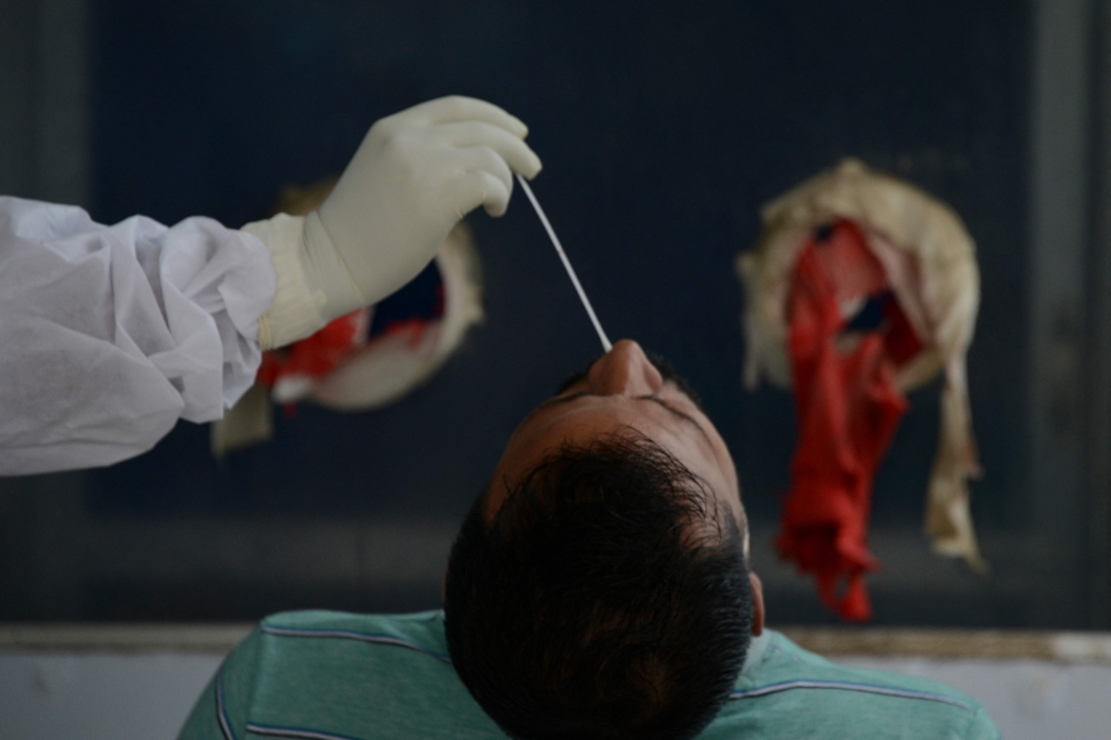 A health worker collects nasal swab for a coronavirus PCR test 