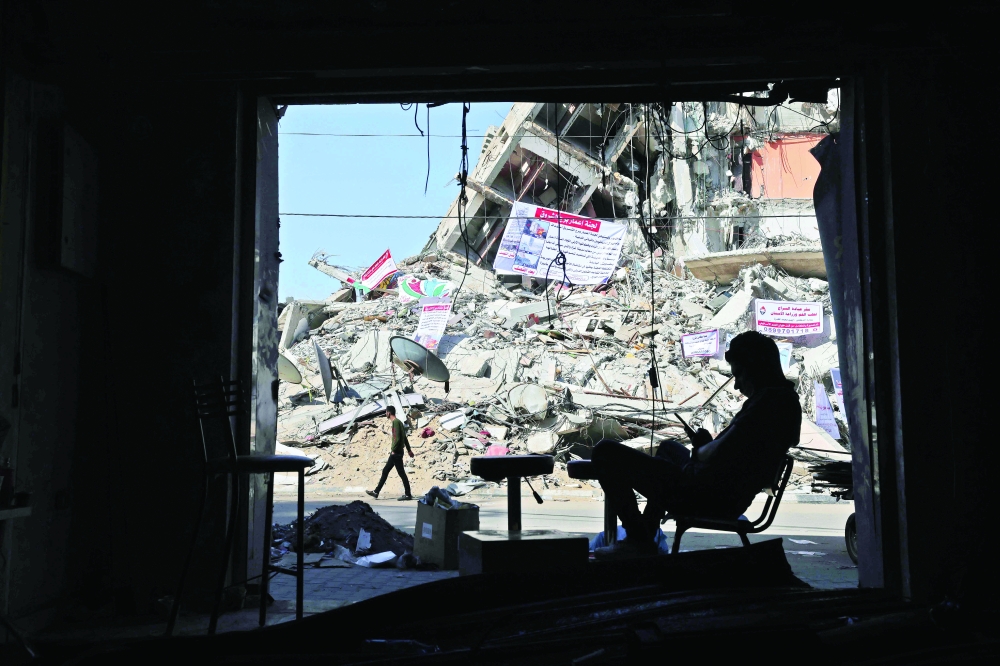 A man sits in a damaged shop at a building partially destroyed in recent Israeli air strikes, in Gaza City, on Wednesday. — AFP