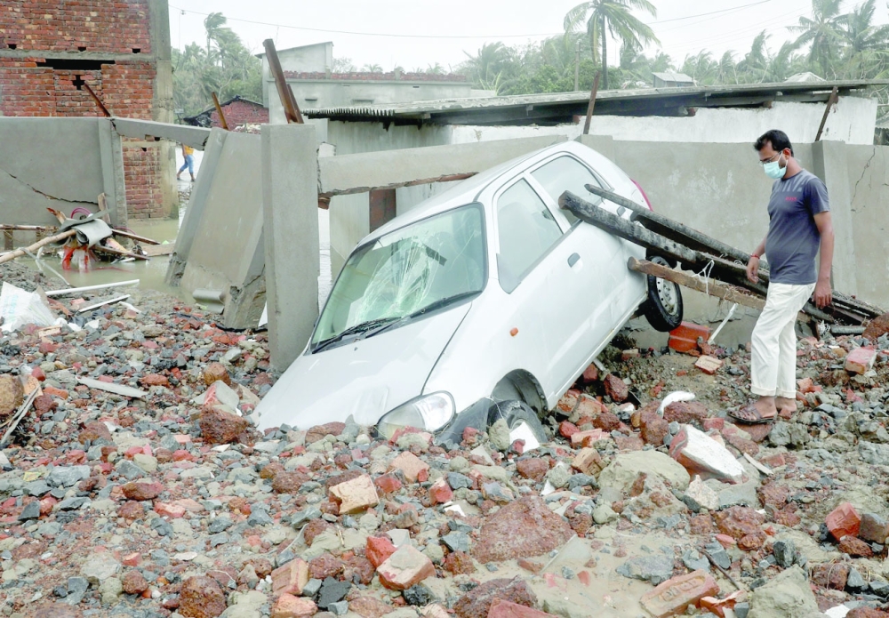 A man walks past a damaged car following Cyclone Yaas in Shankarpur, Purba Medinipur district in West Bengal on Thursday. — Reuters