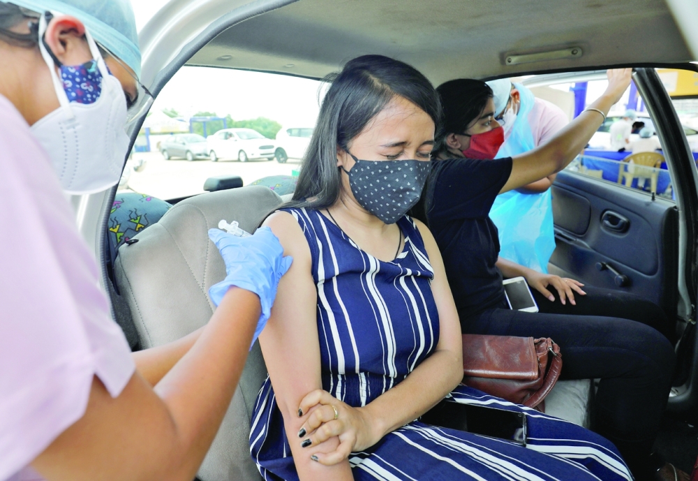 A woman receives vaccine at a drive-in vaccination kiosk in Ahmedabad on Thursday. AFP