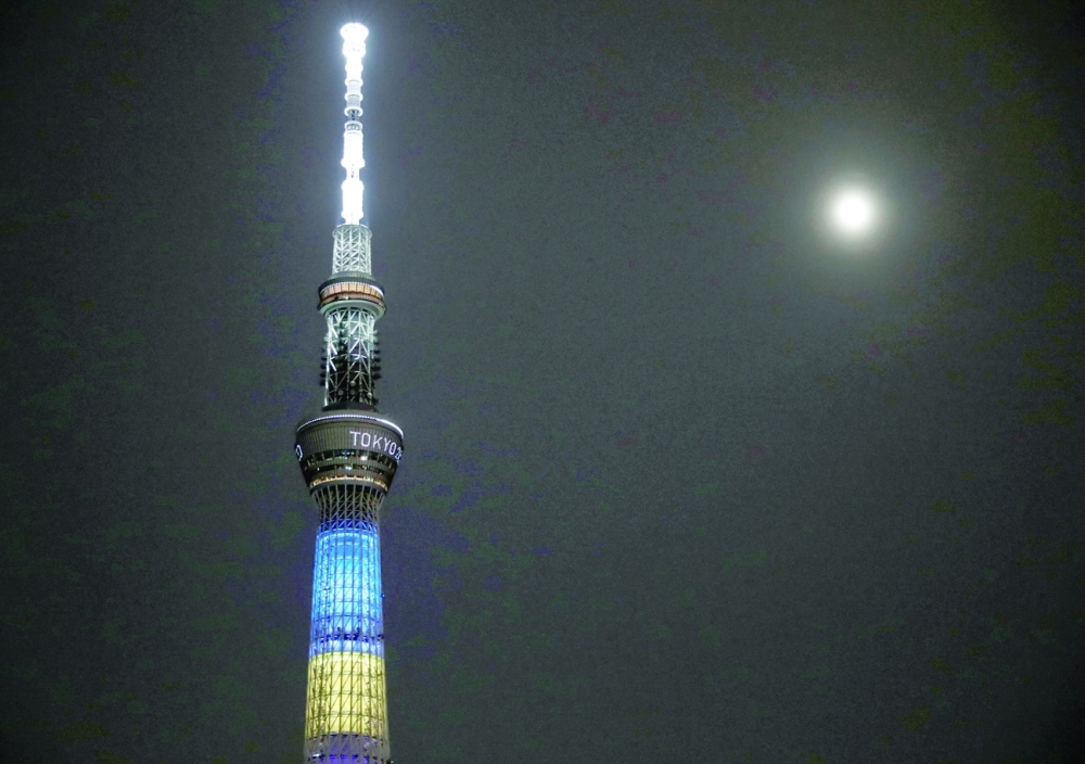 A supermoon, the biggest and brightest full moon of the year, shines next to the Tokyo Skytree which is illuminated in the colors of the Tokyo 2020 Olympic Games, in Tokyo. -- Reuters