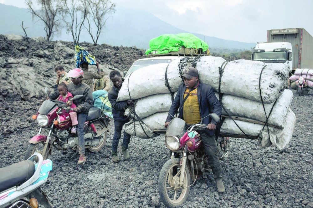Goods transporters ride their motorcycles through the solidified lava flow of Nyiragongo volcano in the northern neighbourhoods of Goma. - AFP 