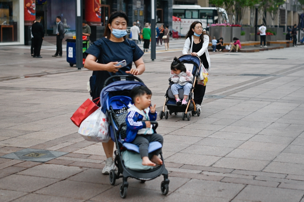Two women push strollers along a business street in Beijing on May 31, 2021. / AFP / WANG Zhao

