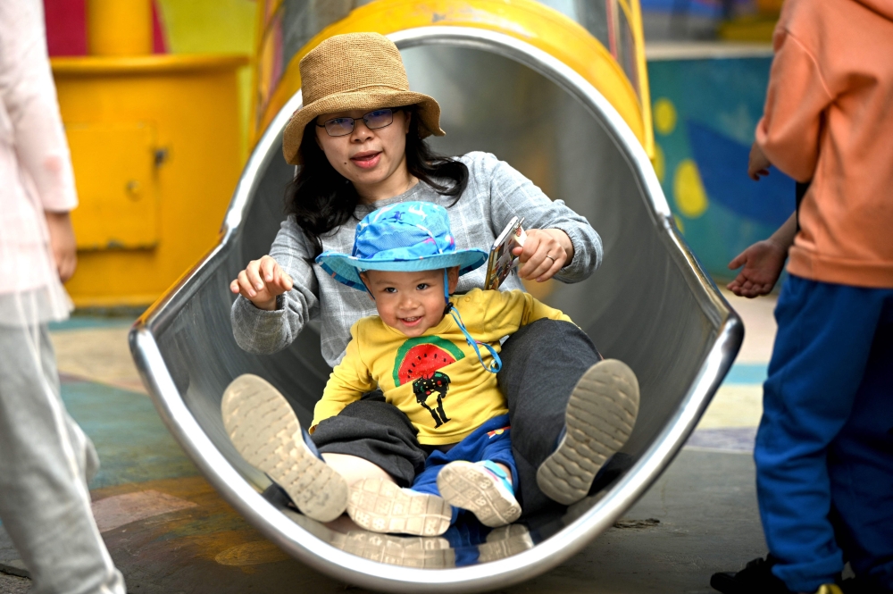  A mother and her baby playing on a slide at the Wukesong shopping district in Beijing. 