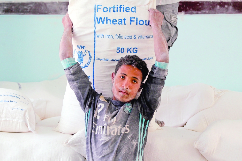 Yemenis receive humanitarian aid provided by the World Food Programme (WFP) in Sanaa on Tuesday. — AFP