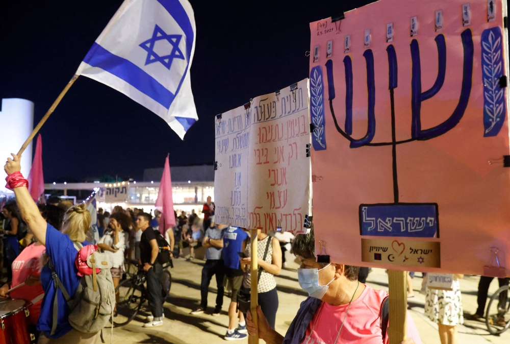 Israeli protesters lift flags and slogans during a demonstration to support Yair Lapid and Naftali Bennett for the formation of a government, on May 31, 2021 in Tel Aviv. Israeli opposition leader Yair Lapid today said many obstacles remain before a diverse coalition can be built to oust veteran Prime Minister Benjamin Netanyahu, but voiced hope it will achieve the "greater goal". Lapid, a secular centrist, has been locked in talks with the right-wing nationalist Naftali Bennett on the terms of a "change alliance" that also hinges on an array of other parties ahead of a Wednesday midnight deadline.
 / AFP / JACK GUEZ

