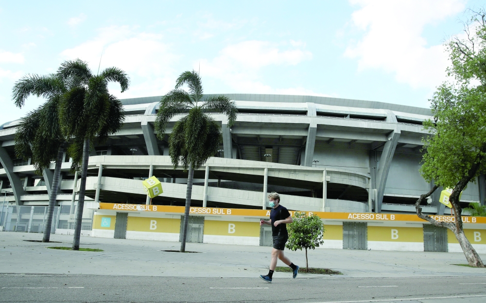 A man wearing a protective mask jogs next to Maracana stadium in Rio de Janeiro, Brazil. -- Reuters