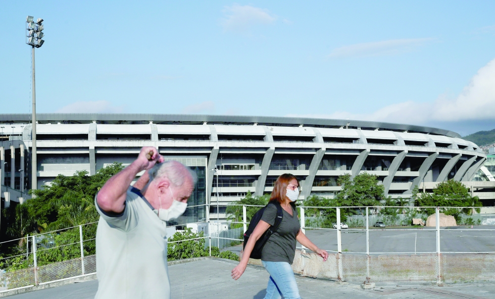 People wearing protective masks walk next to Maracana stadium in Rio de Janeiro, Brazil. -- Reuters