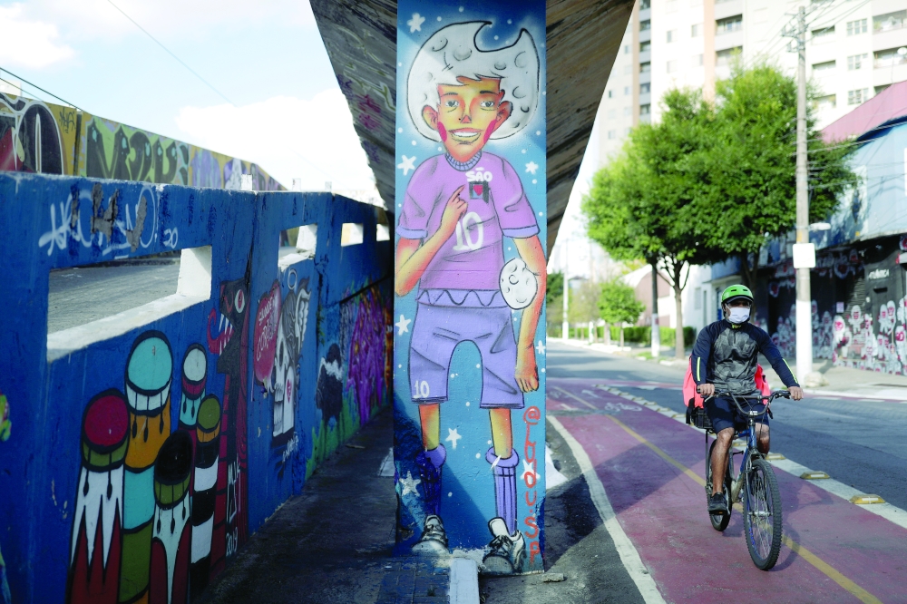A man rides a bike near a graffiti depicting a soccer player in Sao Paulo, Brazil. -- Reuters