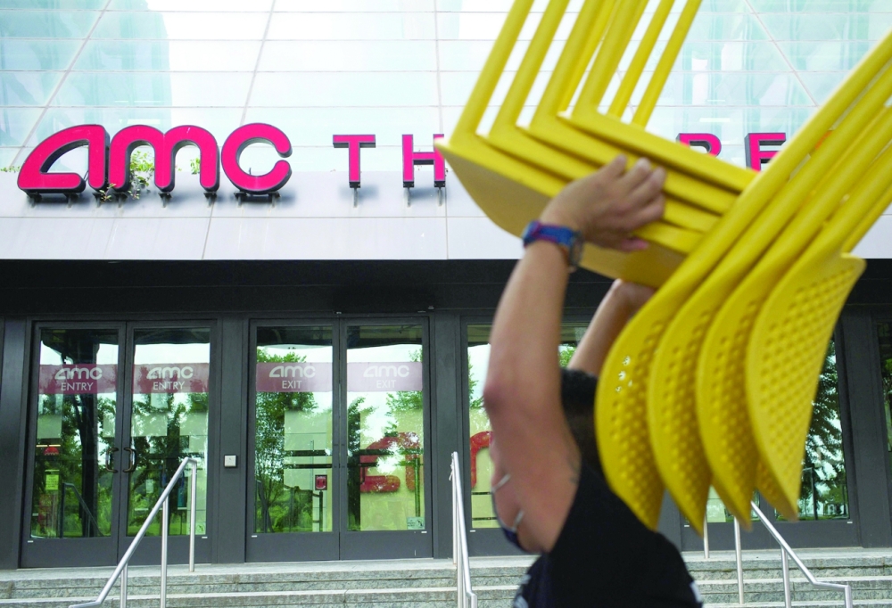 A worker moves a stack of chairs outside of the AMC Georgetown 14 Theatres in Washington, DC. - AFP