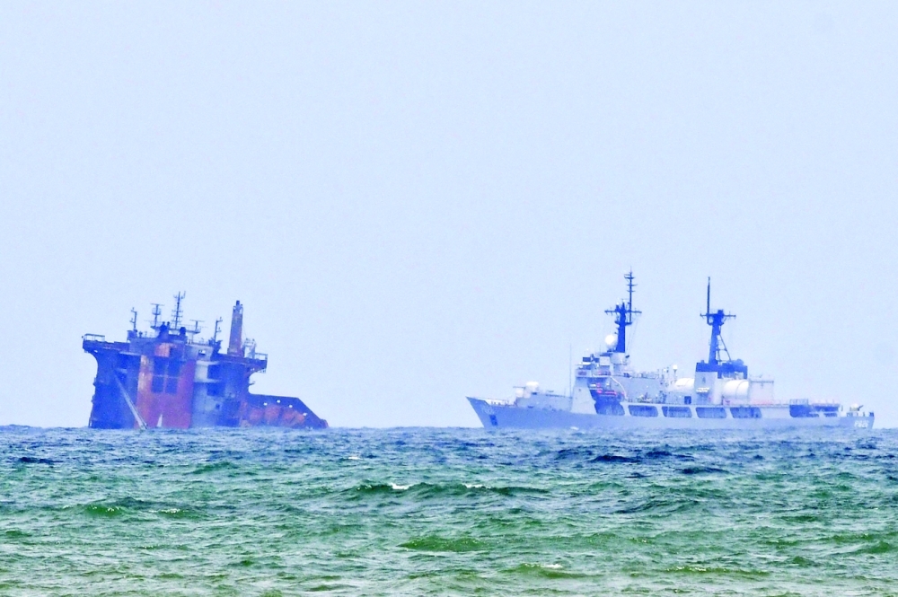 A ship approaches near the Singapore-registered container ship MV X-Press Pearl that partially sunk after burning for almost two weeks, just outside Colombo's harbour. - AFP 