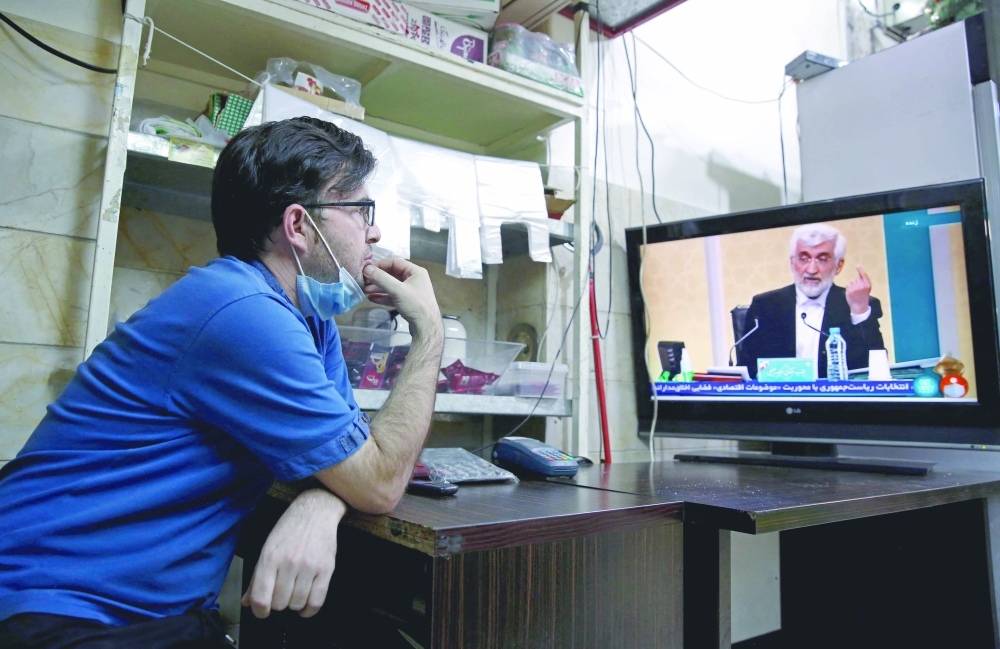 An Iranian vendor watches candidate Saeed Jalili speaking during the first televised debate between Iran presidential candidates at a shop in Tehran. - AFP

